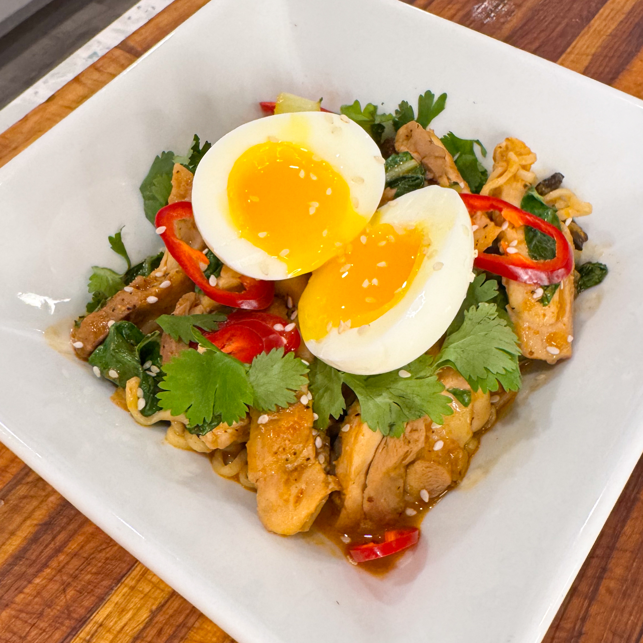 tender chicken, flavorful ramen noodles, and a rich, aromatic coconut broth with a kick from serrano peppers, topped with a perfectly cooked six-minute egg and fresh cilantro